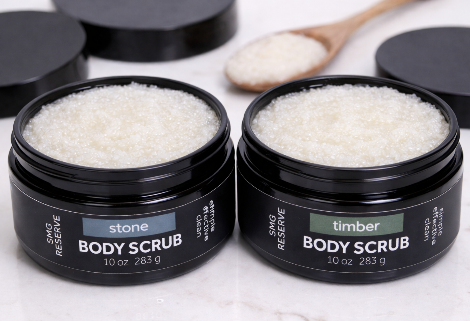 Open jars of SMG Reserve Stone and Timber body scrubs showing white, oil-based sugar scrub texture